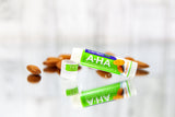 LubriSynHA A-HA lip balm in almond on a mirrored surface surrounded by almonds