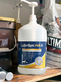 LubriSyn HA pet and equine gallon with pump sitting on barn shelf among other supplements.
